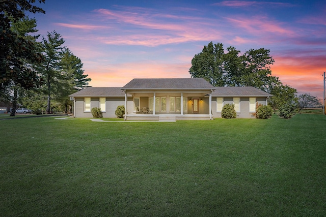 back house at dusk with a yard and covered porch