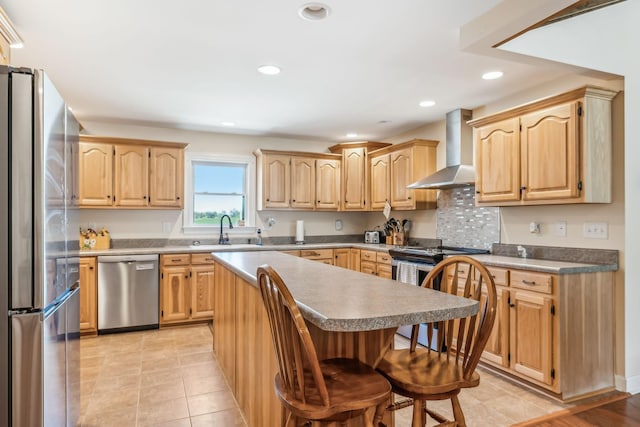 kitchen featuring appliances with stainless steel finishes, a breakfast bar, sink, wall chimney range hood, and a center island