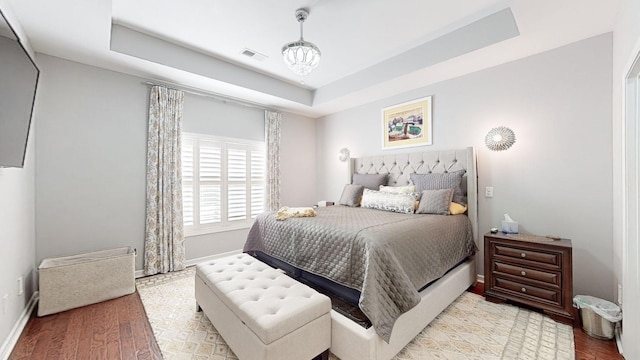 bedroom featuring a raised ceiling and light hardwood / wood-style flooring