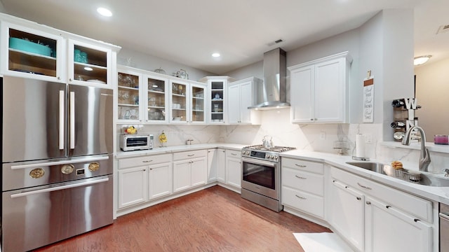 kitchen featuring white cabinetry, sink, wall chimney exhaust hood, stainless steel appliances, and light wood-type flooring