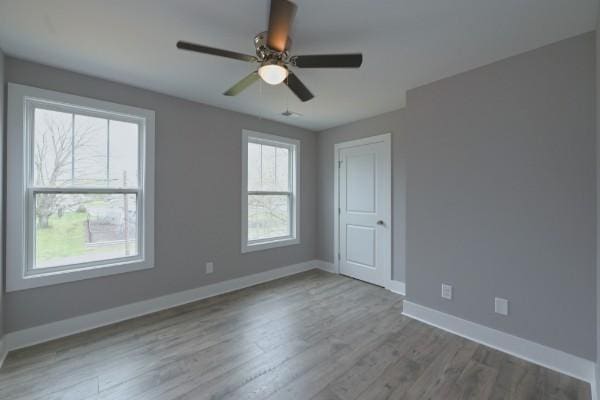 empty room featuring hardwood / wood-style flooring, ceiling fan, and a healthy amount of sunlight