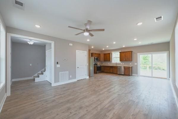 unfurnished living room featuring ceiling fan, light hardwood / wood-style floors, and sink