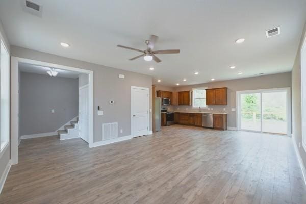 104A N St, Portland, TN 37148 - unfurnished living room featuring light wood finished floors, baseboards, ceiling fan, stairs, and recessed lighting