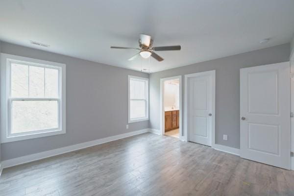 unfurnished bedroom with ceiling fan, light hardwood / wood-style floors, and connected bathroom