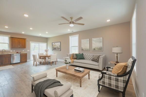 living room featuring sink, light hardwood / wood-style floors, a wealth of natural light, and ceiling fan