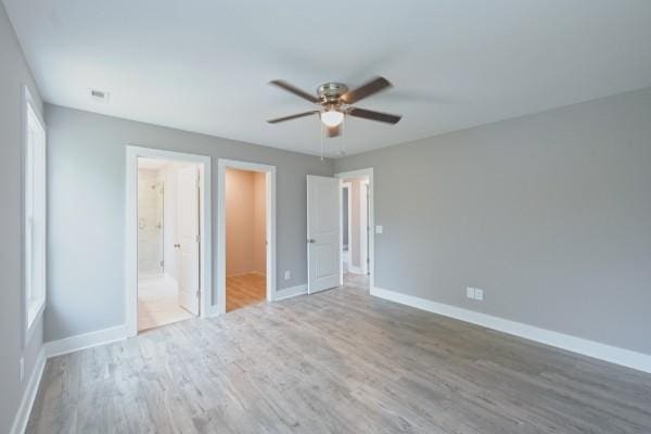 unfurnished bedroom with connected bathroom, ceiling fan, and wood-type flooring