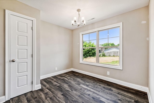 empty room featuring dark wood-style floors, visible vents, a notable chandelier, and baseboards