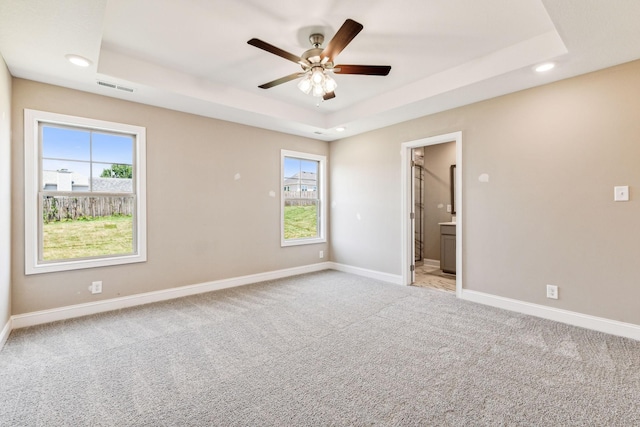 unfurnished bedroom with a raised ceiling, baseboards, visible vents, and carpet floors