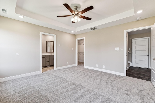 unfurnished bedroom with visible vents, baseboards, carpet floors, a tray ceiling, and recessed lighting