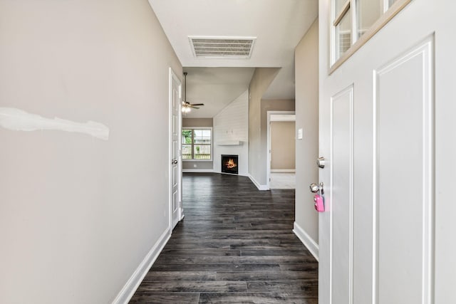 corridor with dark wood-style floors, visible vents, and baseboards