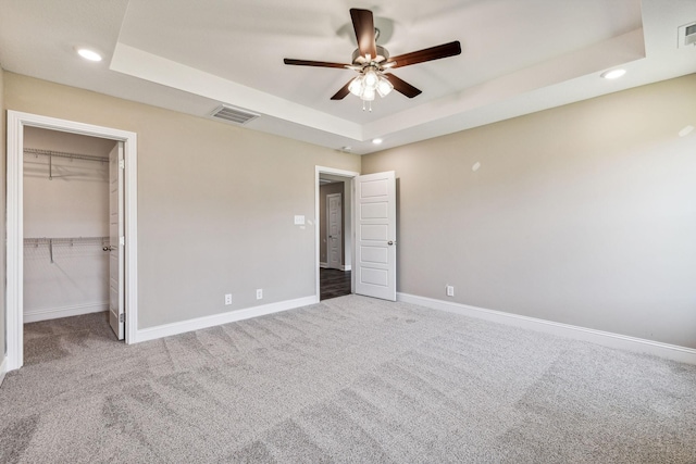 unfurnished bedroom featuring a raised ceiling, carpet, visible vents, and baseboards