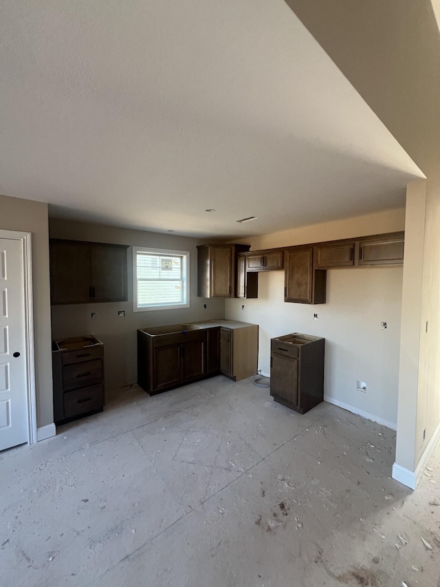 kitchen featuring baseboards and dark brown cabinetry