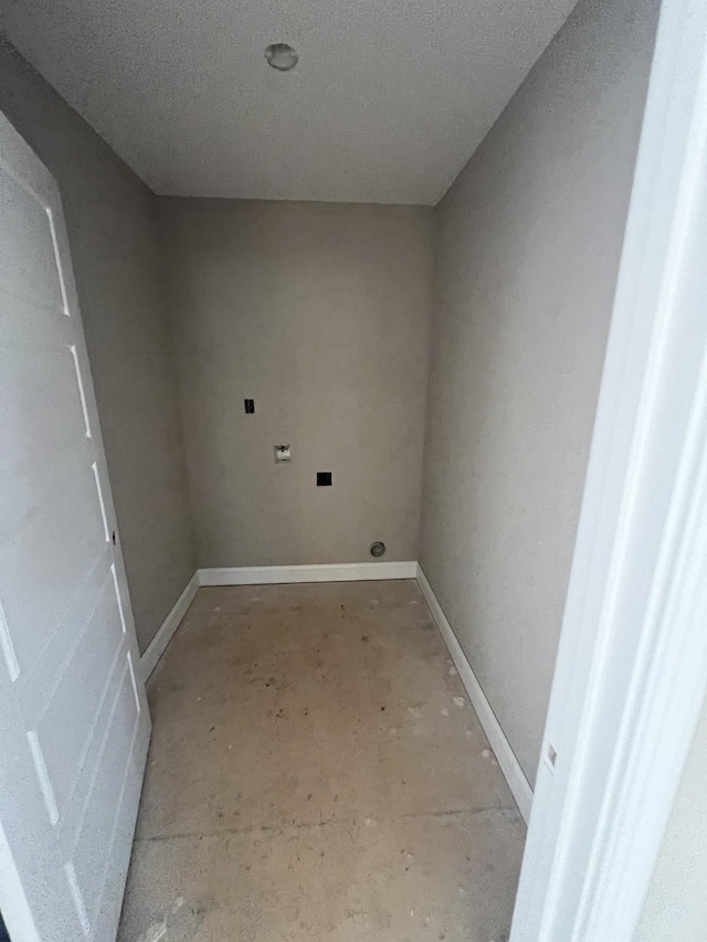 clothes washing area featuring baseboards and a textured ceiling