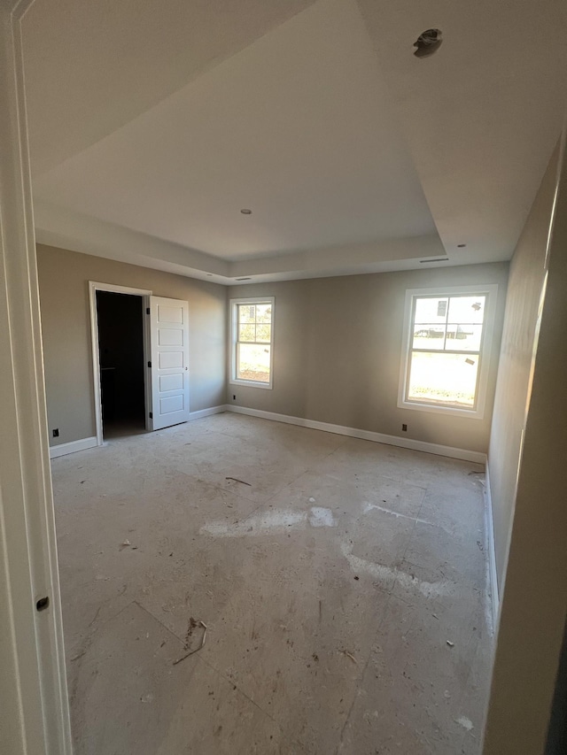 empty room featuring baseboards and a raised ceiling