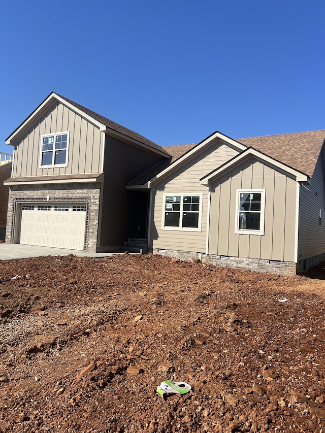 view of front facade with board and batten siding, an attached garage, and a shingled roof