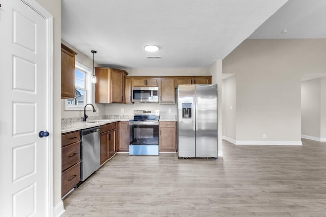 130 Anderson Pl, Clarksville, TN 37042 - kitchen with a sink, brown cabinetry, light wood-type flooring, pendant lighting, and appliances with stainless steel finishes