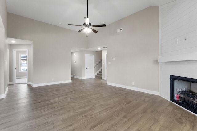 130 Anderson Pl, Clarksville, TN 37042 - unfurnished living room featuring baseboards, a ceiling fan, wood finished floors, a large fireplace, and stairs