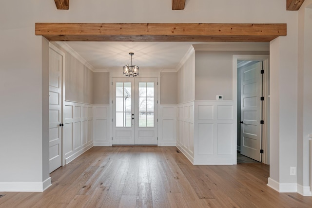 foyer featuring beamed ceiling, french doors, light wood-type flooring, and ornamental molding