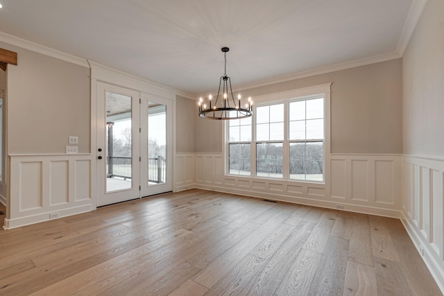 unfurnished dining area featuring an inviting chandelier, light hardwood / wood-style floors, and ornamental molding