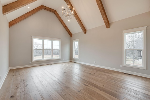 unfurnished living room with beamed ceiling, an inviting chandelier, a wealth of natural light, and light hardwood / wood-style flooring