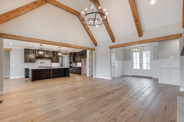 unfurnished living room featuring beamed ceiling, french doors, light wood-type flooring, and high vaulted ceiling