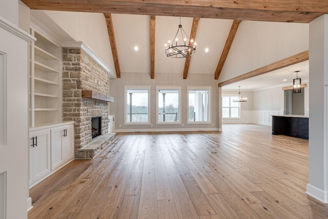 unfurnished living room featuring beam ceiling, a stone fireplace, plenty of natural light, and light hardwood / wood-style flooring