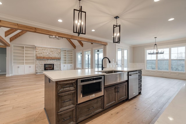 kitchen with a kitchen island with sink, sink, pendant lighting, and light hardwood / wood-style floors