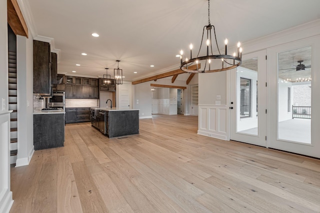 kitchen with a center island with sink, ceiling fan with notable chandelier, decorative light fixtures, light hardwood / wood-style flooring, and dark brown cabinets