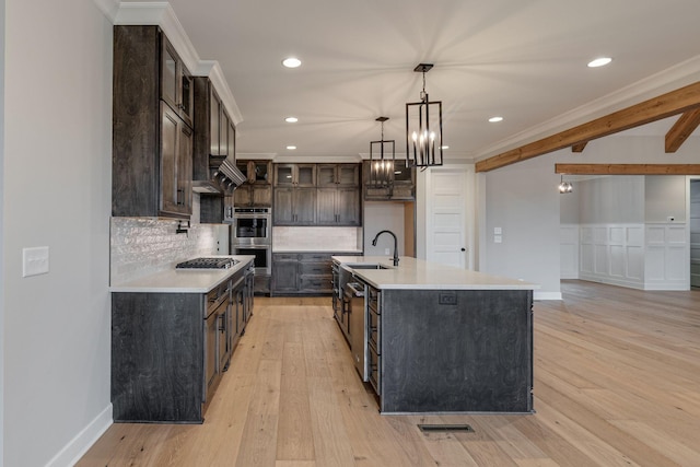 kitchen featuring pendant lighting, a center island with sink, light wood-type flooring, dark brown cabinets, and stainless steel appliances