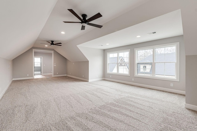 additional living space with light carpet, vaulted ceiling, a wealth of natural light, and ceiling fan