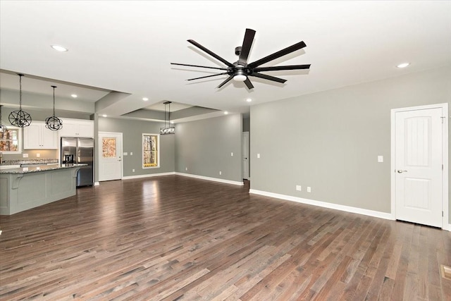 unfurnished living room featuring dark hardwood / wood-style flooring and ceiling fan