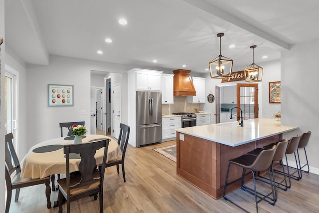 kitchen featuring premium range hood, white cabinets, sink, light hardwood / wood-style flooring, and stainless steel appliances