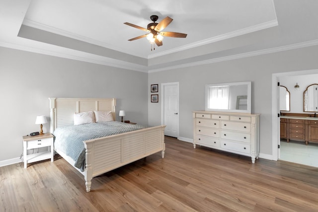 bedroom featuring a raised ceiling, connected bathroom, ceiling fan, and hardwood / wood-style flooring