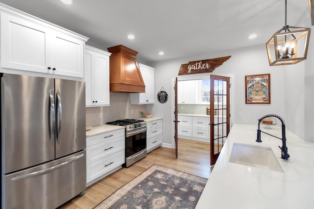 kitchen with appliances with stainless steel finishes, custom exhaust hood, sink, light hardwood / wood-style flooring, and white cabinetry