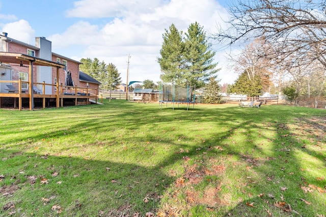 view of yard with a trampoline and a deck