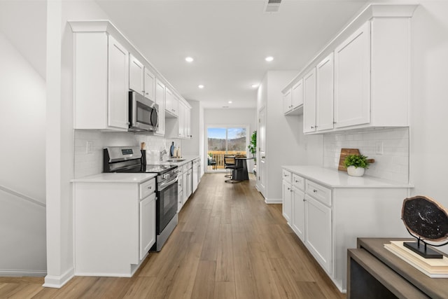 kitchen featuring white cabinetry, light wood-type flooring, and appliances with stainless steel finishes