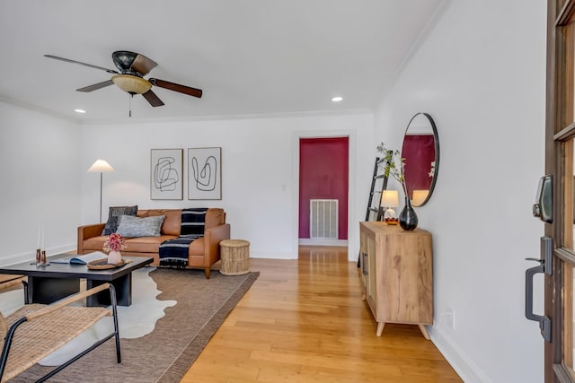 living room featuring ceiling fan, light hardwood / wood-style floors, and ornamental molding