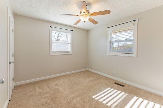 empty room with light carpet, a textured ceiling, and ceiling fan