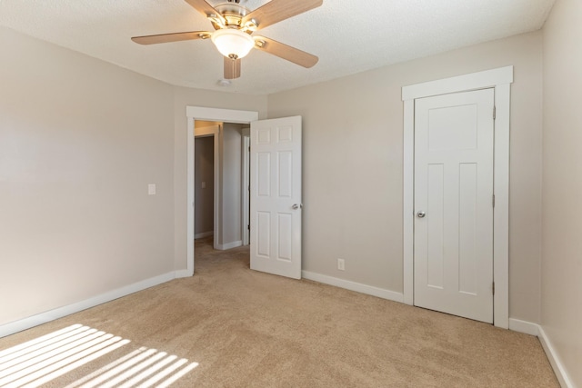 unfurnished bedroom featuring a textured ceiling, ceiling fan, light carpet, and a closet