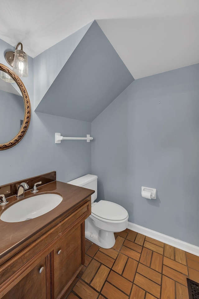 bathroom featuring vanity, toilet, and lofted ceiling