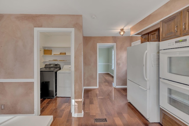 kitchen with hardwood / wood-style floors, washing machine and dryer, and white appliances