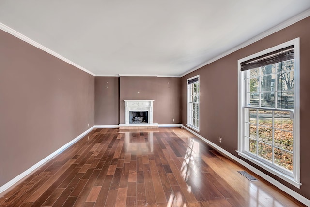 unfurnished living room featuring wood-type flooring, ornamental molding, and a wealth of natural light