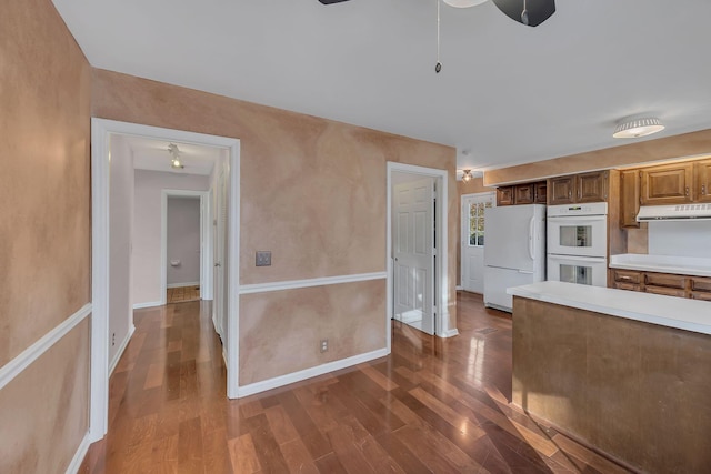 kitchen with ceiling fan, white appliances, and dark wood-type flooring