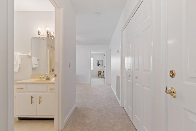 hallway featuring sink and light colored carpet