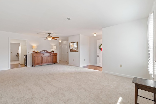 unfurnished living room featuring light carpet, ceiling fan, and a healthy amount of sunlight