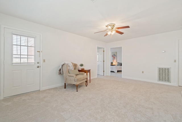 living area with ceiling fan and light colored carpet