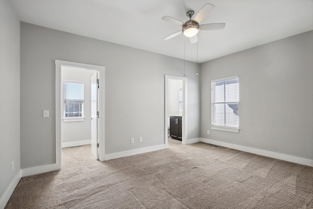 unfurnished bedroom with a walk in closet, ceiling fan, ensuite bathroom, and light colored carpet