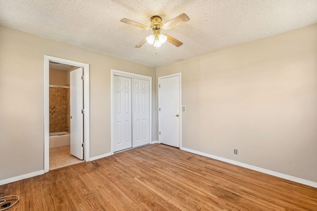 unfurnished bedroom featuring a textured ceiling, light wood-type flooring, ensuite bathroom, and ceiling fan