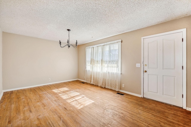 interior space with hardwood / wood-style floors, a textured ceiling, and an inviting chandelier