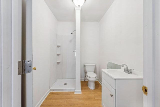 bathroom featuring wood-type flooring, vanity, toilet, and walk in shower